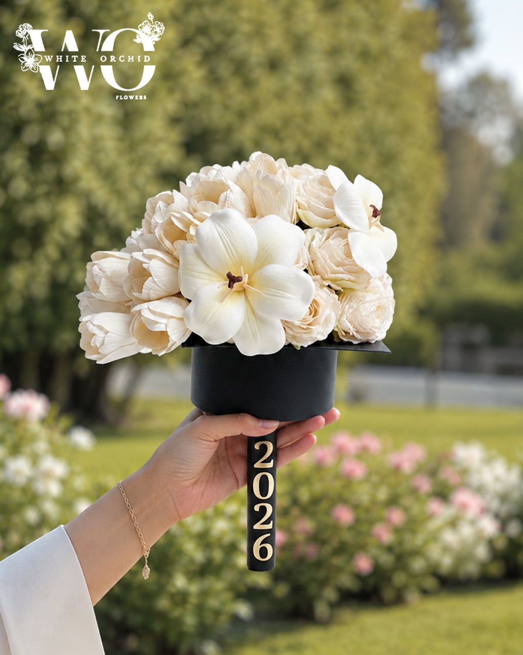 White graduation flower arrangement in a graduation cap design with elegant white blooms and orchid accents.