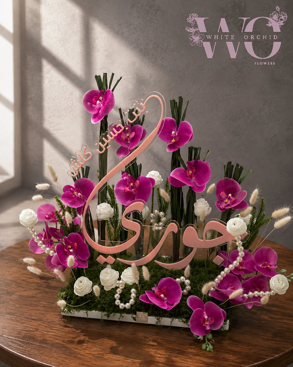 Baby girl floral arrangement with pink orchids, peach chrysanthemums and white flowers on a marble base