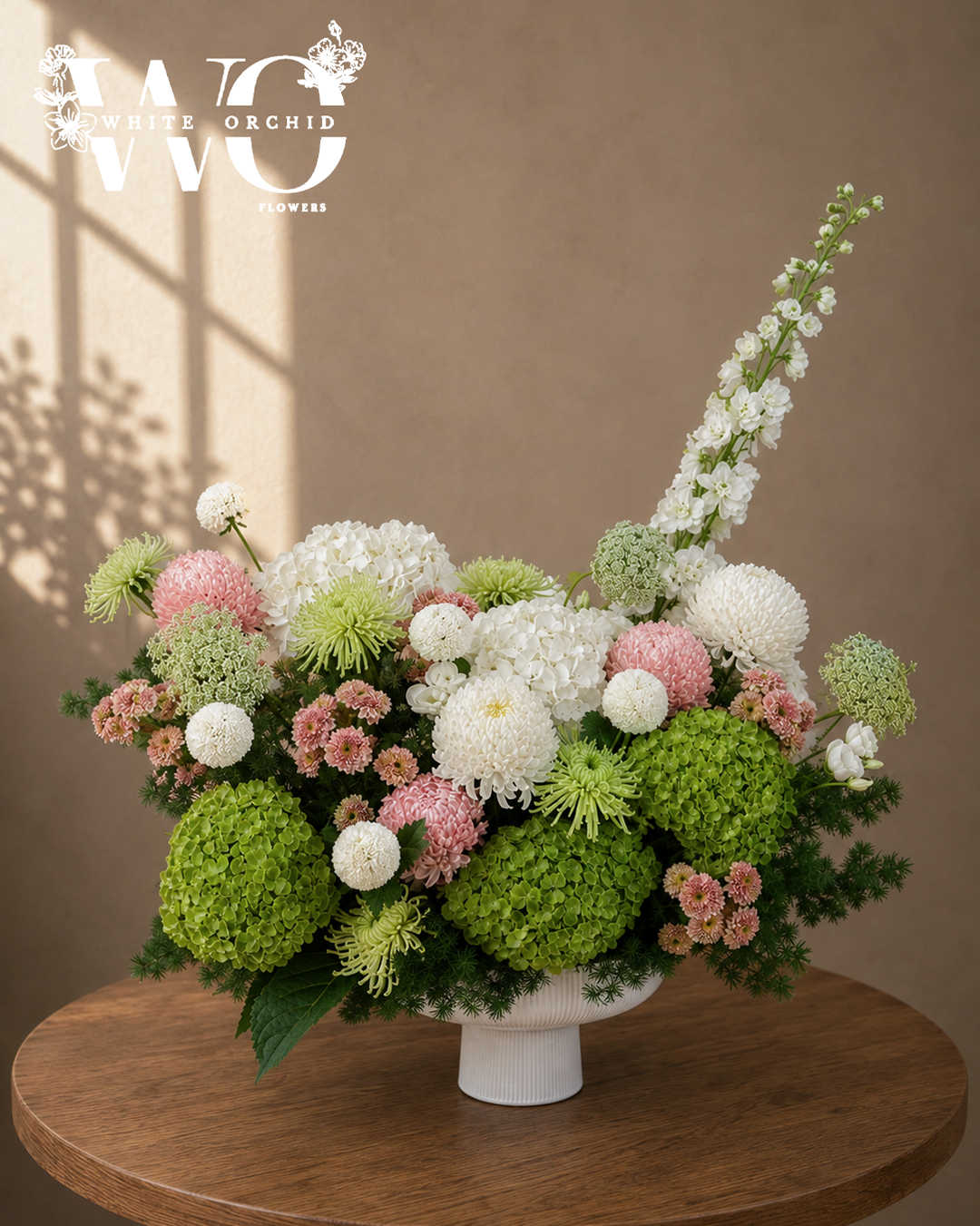 Green and pink luxury flower arrangement with hydrangeas, chrysanthemums and white blooms in a white pedestal vase