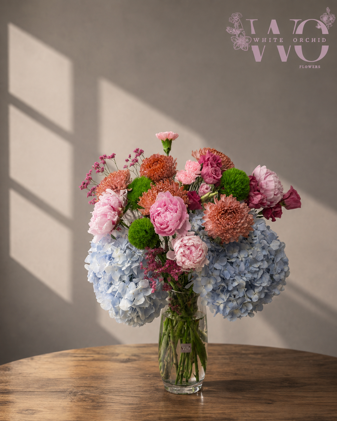 Luxury blush pink and blue hydrangea bouquet with peonies and chrysanthemums in a glass vase