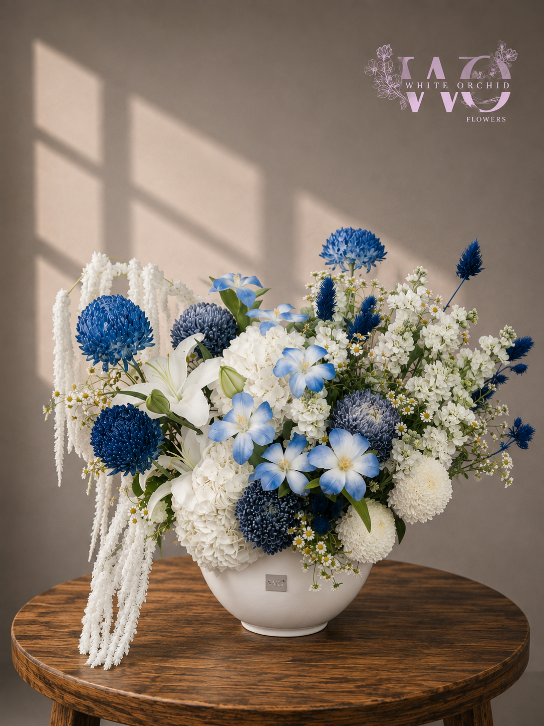 Luxury blue and white flower arrangement with chrysanthemums, hydrangeas, lilies and delicate flowers in a white ceramic vase
