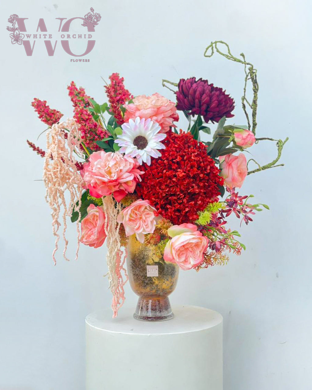 Artificial flower arrangement in decorative vase with mixed colorful flowers by White Orchid Flowers UAE.