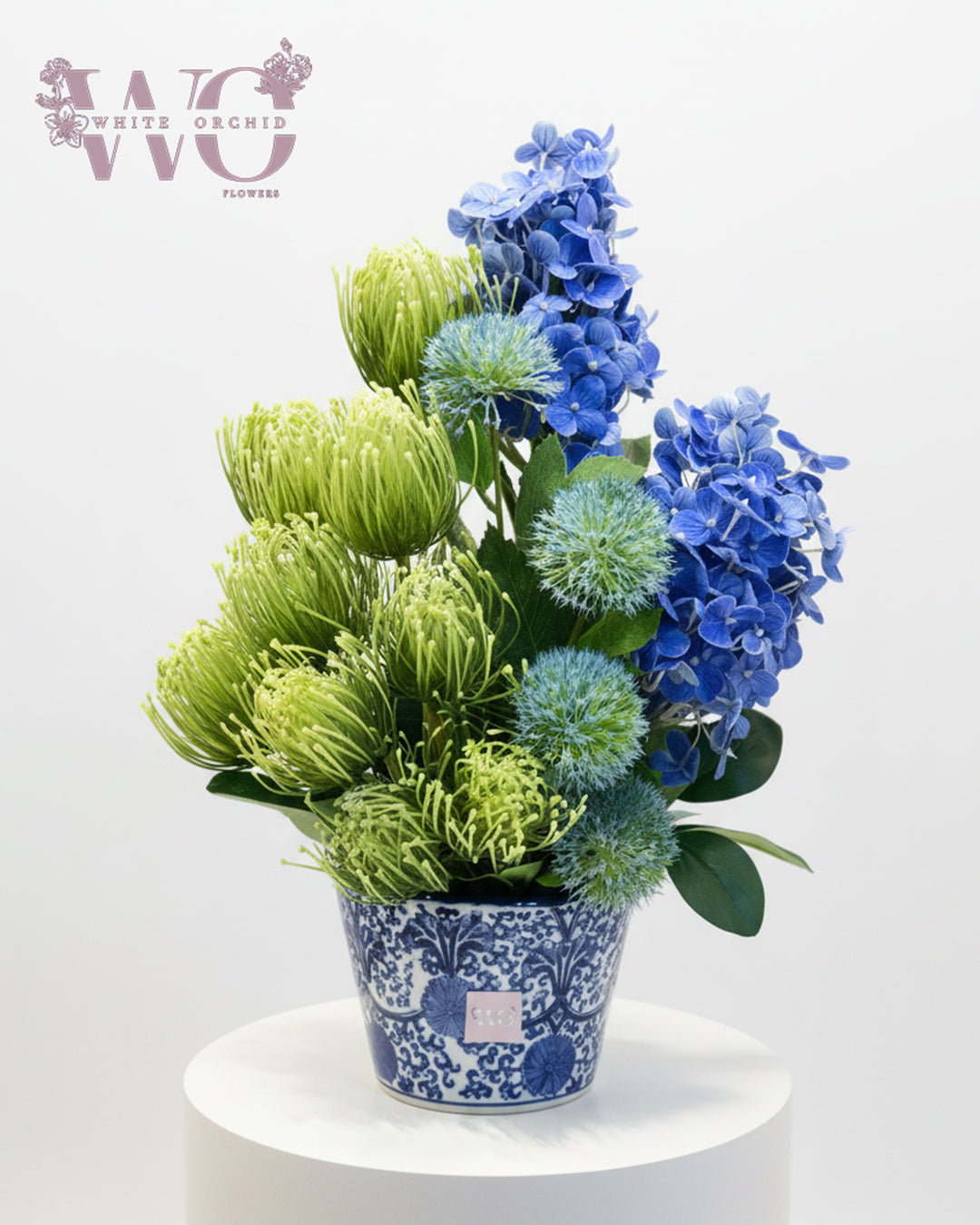 Artificial blue hydrangea and green flower arrangement in decorative vase by White Orchid Flowers UAE.