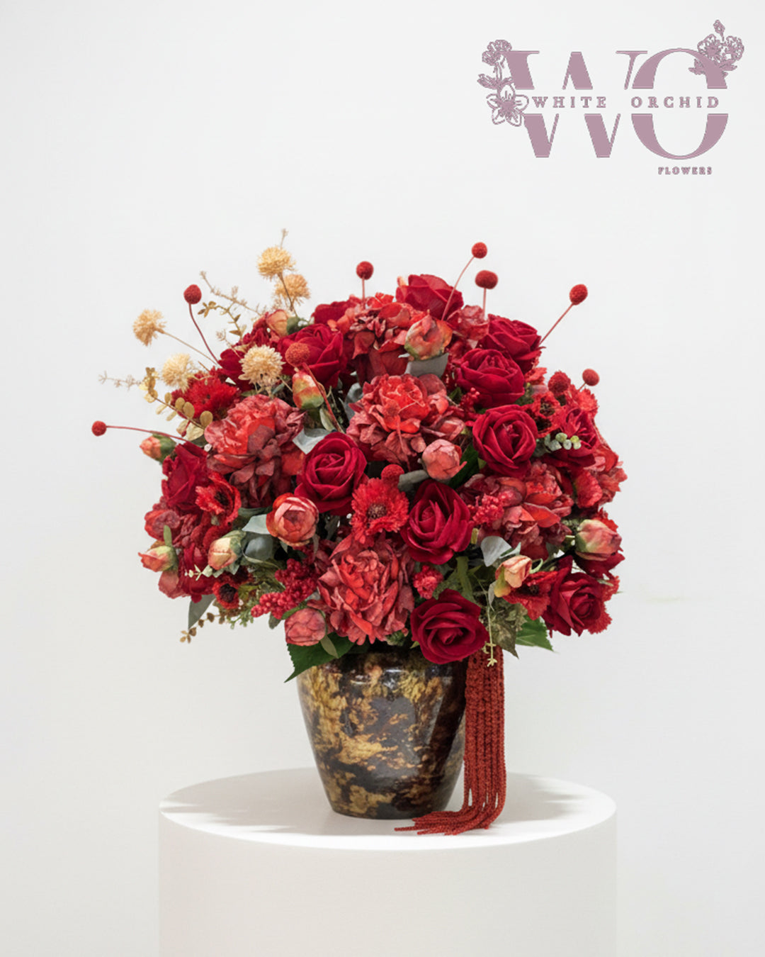 Luxury artificial red flower arrangement with roses and mixed blooms in decorative vase.