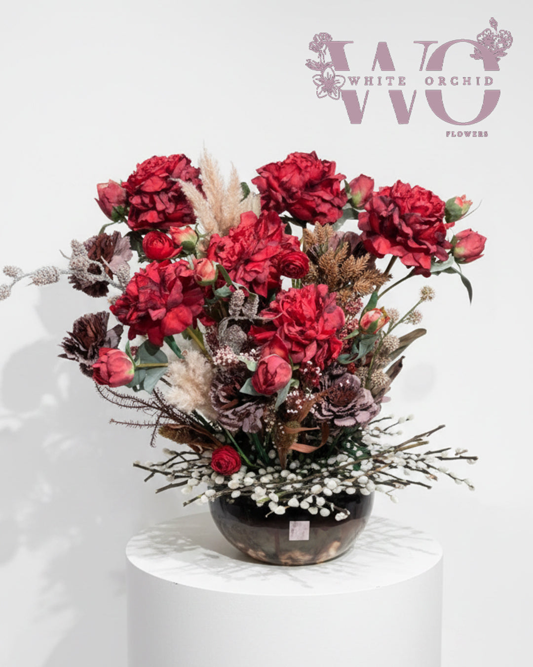 Artificial red floral arrangement with mixed flowers in decorative vase.