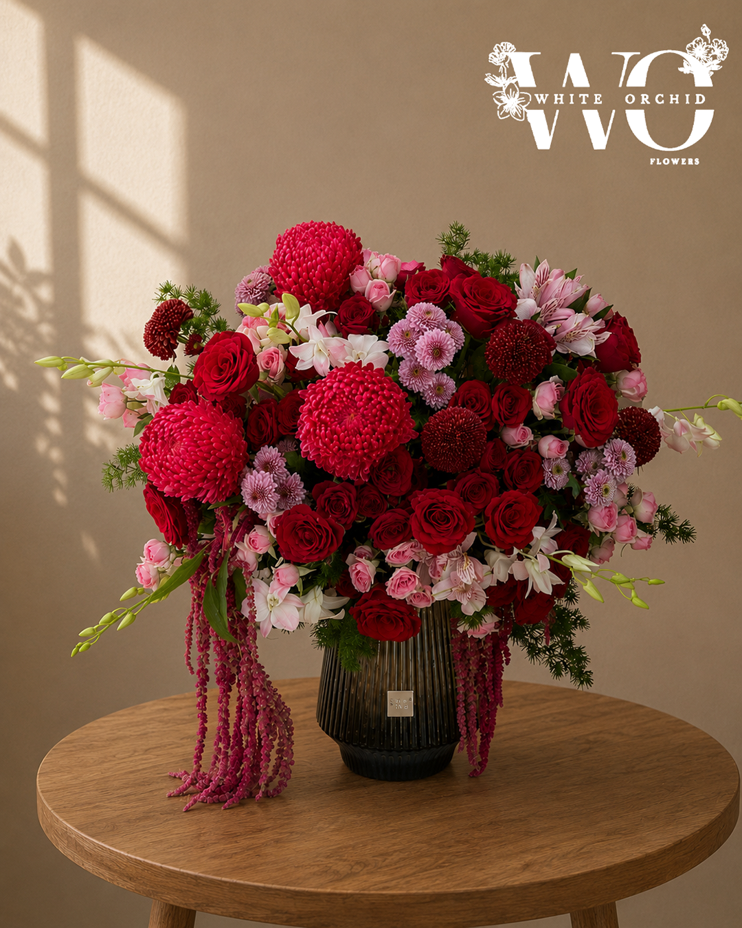 Luxury red and pink flower arrangement with roses, chrysanthemums, lilies and cascading amaranthus in a black vase